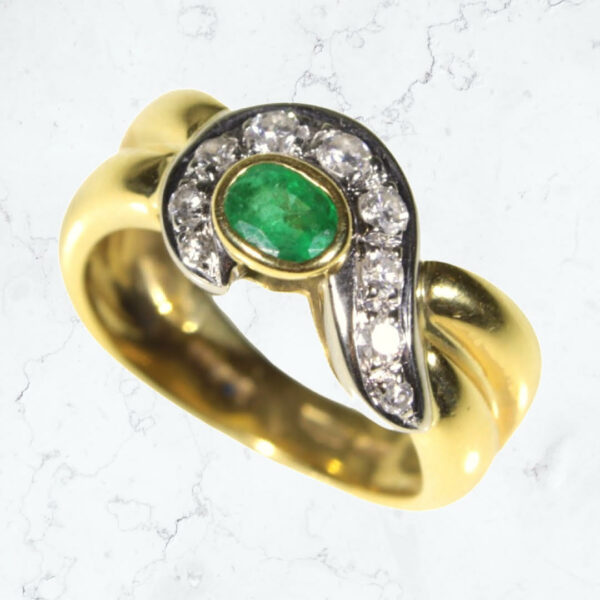The glorious color of emerald, wrapped in a cascade of sparkling diamonds! Here is the rich tone of an 18 karat ladies' fashion ring, with nine eye-popping round brilliant diamonds, circling around a gorgeous green emerald. Think spring, think the holidays, think any time at all! The ring is a size 7. WAS $3,129. IS $2,499 now at Airport Plaza Jewelers, The Showroom on Union. One only.