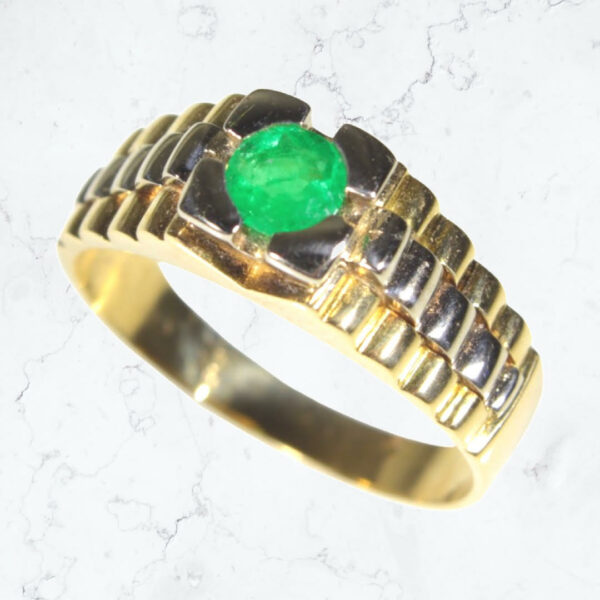 This is a grand, 18 karat two-tone gold men's fashion ring. Perched atop a cascading Rolex-style pattern, it's crowned with the rich color of a beautiful emerald. This ring is the perfect match for a man who loves a splash of green. The ring is size 10. WAS $2,499. IS $1,999 now at Airport Plaza Jewelers, the Showroom on Union. SKU 205-200. One only. Look for our bright red awning at 4230 Union Road, Cheektowaga.